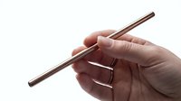 Hand holding a reusable rose gold metal straw, eco-friendly sustainable drinking alternative, zero waste lifestyle concept on white background.