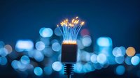 Glowing sparklers in bottle against blurred city lights creating magical bokeh effect in blue tones, festive celebration atmosphere at night.