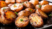 Roasted baby potatoes with herbs and seasoning in cast iron skillet. Golden brown crispy skin with tender interior. Home cooking and comfort food concept.
