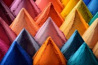 Vibrant piles of colorful powder pigments arranged in geometric peaks, showcasing rich hues from deep blue to bright yellow and orange. Macro photography reveals texture detail.