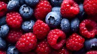 Fresh ripe raspberries and blueberries with water drops in macro view, natural organic berries background for healthy eating and food design.