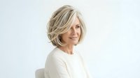 Mature woman with shoulder-length blonde hair wearing cream-colored top, smiling at camera against white background. Suitable for healthcare, wellness, lifestyle and corporate business applications.