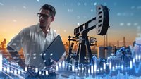 Middle-aged Caucasian engineer with glasses analyzing data at oil drilling site with pump jack and digital financial charts overlay at sunset.