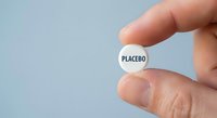 Hand holding white pill with placebo text for medical research, pharmaceutical testing, clinical trials, and healthcare education concepts.
