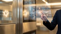 Businessman touching digital network interface with glowing connections in modern elevator, representing connectivity and smart building technology.