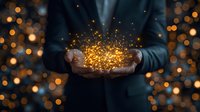 Magical glowing golden sparkles and light particles floating above cupped hands against dark background with bokeh effect, creating mystical atmosphere.