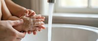 Close-up of hands washing with soap under running water faucet in bathroom sink. Personal hygiene and cleanliness routine for health and wellness.