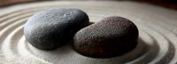 Smooth black and brown zen stones on raked sand creating peaceful balance, perfect for wellness, meditation, and spa concepts.