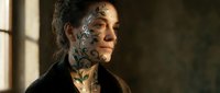 Mature Caucasian man with extensive facial tattoos and long hair in dramatic lighting, showcasing alternative lifestyle and body art culture for editorial content.