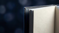 Open book with blank pages against dark blue bokeh background for education and reading concepts.