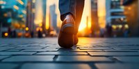 Close-up of person walking on cobblestone street at sunset, leather shoe stepping forward with golden sunlight and urban bokeh lights in background.