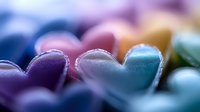 Colorful heart shapes in soft focus with purple and blue pastel tones creating romantic dreamy atmosphere. Macro photography captures delicate details and bokeh effect.