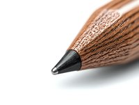 Sharp graphite pencil tip in extreme macro closeup showing detailed wood texture and lead point against white background, minimalist composition for creative design.