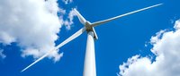 Modern wind turbine against bright blue sky with white clouds generating clean renewable energy for sustainable power production and environmental conservation.