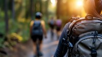 Hikers wearing backpacks walking on forest trail at sunset, outdoor adventure and trekking activity for travel and nature exploration.