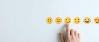 Caucasian hand selecting happy yellow smiley face emoji from row of emotion icons on white background, representing customer satisfaction, feedback, and user experience rating.