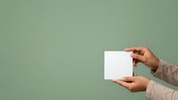 Close-up of hands holding blank white card against sage green background, suitable for business branding, stationery mockups, and marketing presentations.