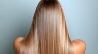 Young woman with long straight blonde ombre hair shown from behind against light blue background, demonstrating healthy, shiny hair after salon treatment.