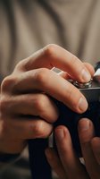 Close-up of male hands adjusting vintage camera settings with shallow depth of field background for photography and creative projects.