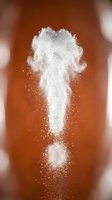 White powder explosion cloud with particles dispersing against warm brown background creating dynamic motion effect for creative design projects.