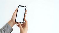 Hands holding smartphone with blank white screen against neutral background for app mockup and digital marketing campaigns.