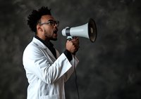 African American male doctor in white coat and glasses shouting through megaphone against dark background, expressing urgency and communication in healthcare.
