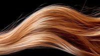 Flowing copper and caramel colored hair strands create elegant wave pattern against dark background, showcasing natural shine and healthy texture for beauty and salon designs.