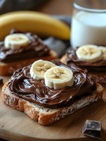 Chocolate hazelnut spread on toasted bread slices topped with fresh banana rounds served with milk glass for nutritious breakfast or snack meal.
