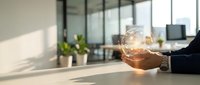 Business professional holding glowing light bulb in modern office workspace representing innovation creativity and bright ideas for corporate success.
