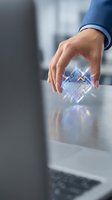 Businessman in blue shirt holding glowing circuit board chip with digital light effects over desk, representing technology innovation and digital transformation for business solutions.