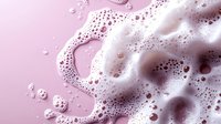 White soap foam and bubbles on pink background, macro photography with soft focus effect showing delicate texture and patterns of cleaning product lather.