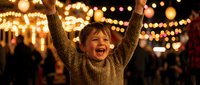 Joyful young boy with arms raised celebrating at festive evening market with warm bokeh lights creating magical holiday atmosphere for family content.