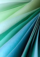 Abstract curved paper sheets in gradient colors from mint green to deep turquoise creating dynamic diagonal lines and soft textured layers for modern design backgrounds.