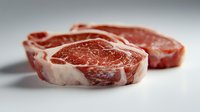 Fresh raw ribeye beef steaks with white marbling on light background, close up view of premium meat cuts for grilling or cooking preparation.
