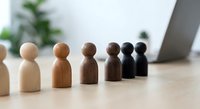 Wooden figurines in gradient from light to dark representing diversity, inclusion and equality concepts in modern office workspace for business presentations.