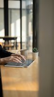 Woman using digital tablet at wooden table in modern office with coffee cup and succulent plant for business productivity and remote work.