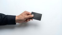 Business professional hand holding black credit card against clean white background for financial services and payment solutions.