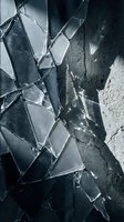Shattered glass fragments with sharp edges creating dramatic cracks and reflective surfaces against dark textured background for design projects.