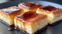 Golden caramelized custard squares with glossy burnt sugar topping on white plate. Traditional flan dessert portions ready for serving at restaurant or bakery.