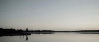 Serene lake at dawn with silhouetted lighthouse and calm reflective waters creating peaceful minimalist landscape for meditation and relaxation themes.