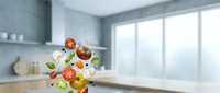 Fresh vegetables falling in modern kitchen with white countertops and gray walls. Cooking ingredients floating in air for healthy meal preparation.