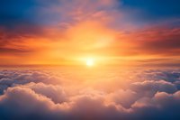 Majestic sunset above fluffy white clouds with vibrant orange and blue sky, aerial view showing dramatic sunburst through cloudscape for spiritual and inspirational designs.