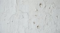 Cracked white painted wall surface showing peeling paint and weathered texture for vintage grunge backgrounds and distressed design projects.