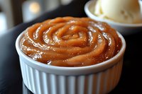 Golden caramel sauce in white ceramic ramekin with glossy swirled texture for dessert topping, baking recipes, and culinary presentations.
