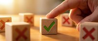 Hand selecting wooden cube with green checkmark among blocks with red X marks, representing choice, decision making, quality control and business success.