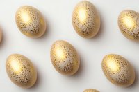 Golden speckled eggs arranged in rows on white background, metallic pattern creates luxurious Easter decoration effect. Minimal holiday composition.