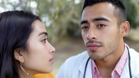Young Asian couple in romantic moment outdoors, close-up portrait of faces showing emotional connection and tenderness against natural blurred background.