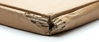 Damaged brown cardboard box corner showing wear and tear from shipping or storage use in logistics and packaging industry.