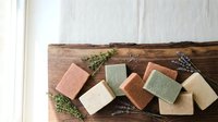 Handmade natural soap bars with herbs on rustic wooden board. Organic skincare products for spa, wellness and eco-friendly bathroom essentials.