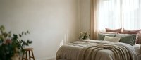 Serene bedroom interior with striped bedding, decorative pillows, potted plants, wooden stool, and natural light from sheer curtains for home decor and design projects.